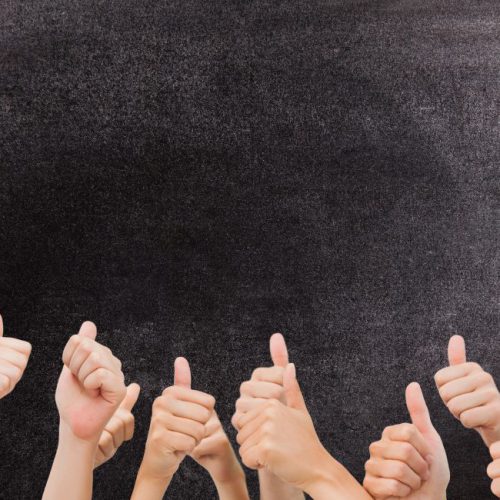 digital composite of multiple thumbs up on chalkboard background